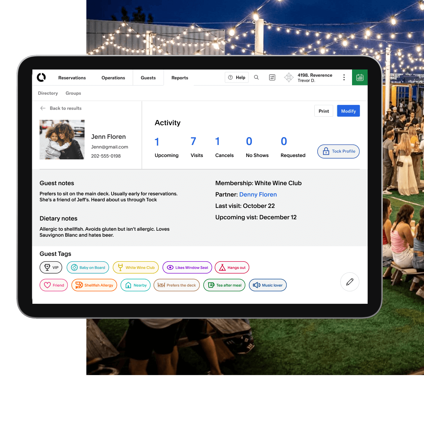 A tablet view showing guest data that a restaurant can see on Tock. The data is for a woman named Jenn Floren and the page contains details on guest notes, dietary notes, guest tags, reservation information, membership details, family information, and contact info. This is layered over an image of various people sitting at tables in the lawn.