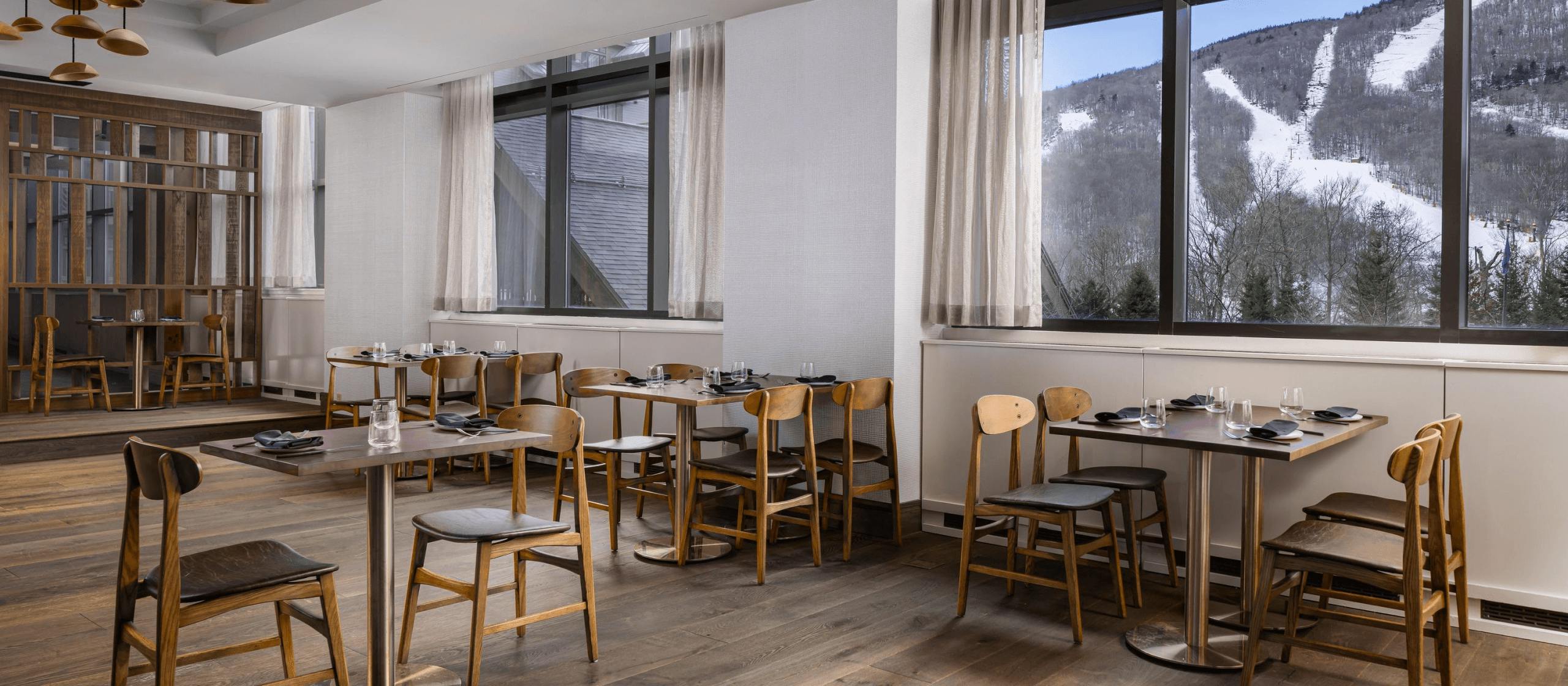 A restaurant's dining room with views of mountains in the background.