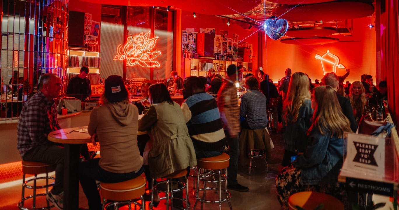 Loveless Cocktail Club - patrons sitting on barstools in a red neon lit cocktail bar
