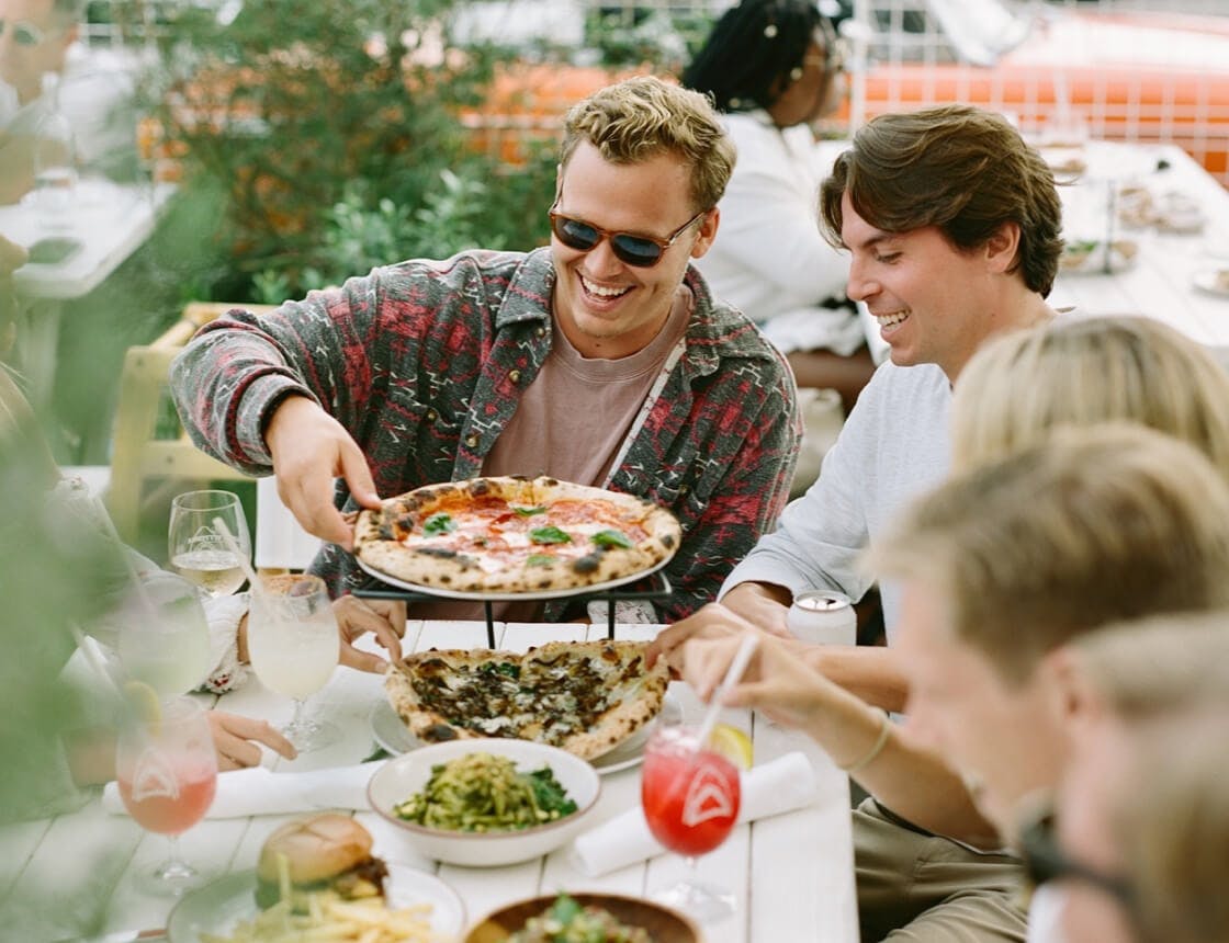 People dining outdoors with neapolitan pizza