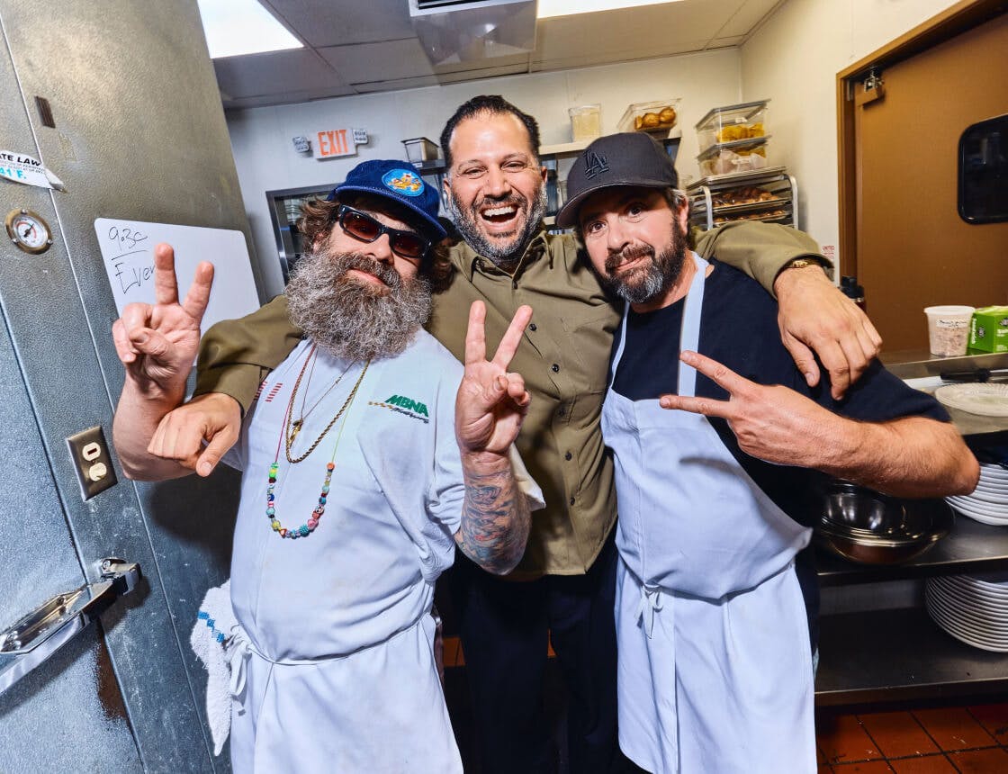 Chefs and owner taking a moment with peace signs towards the camera