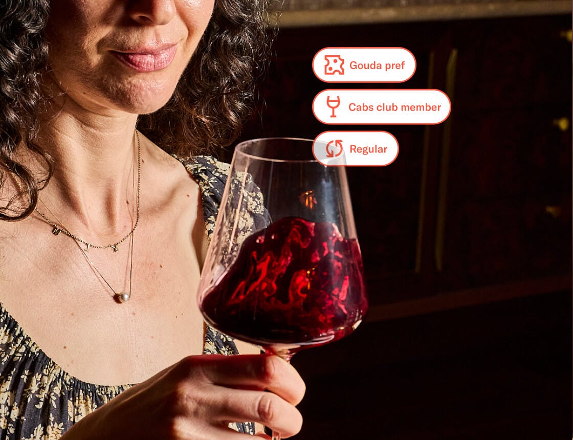 person observing red wine in a glass with guest preference UI overlay