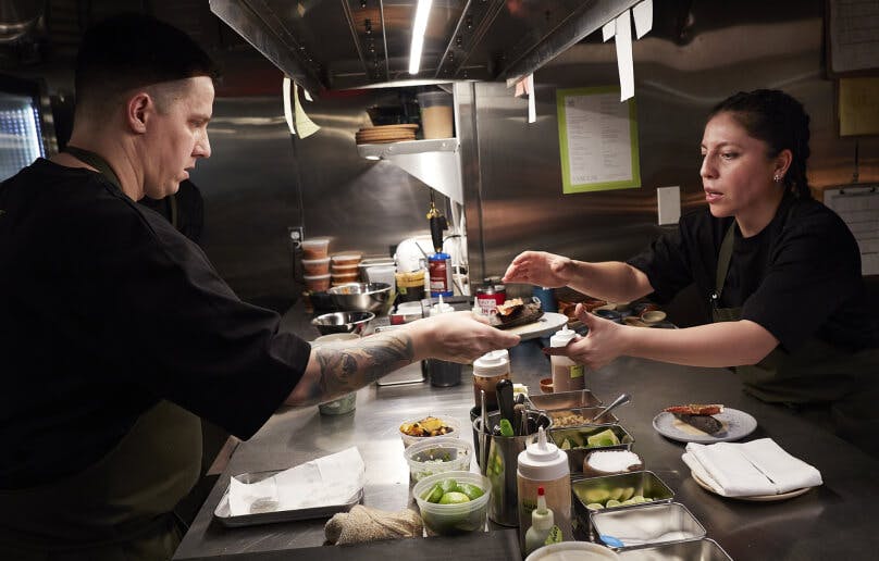 Chefs preparing food with natural light in an open kitchen