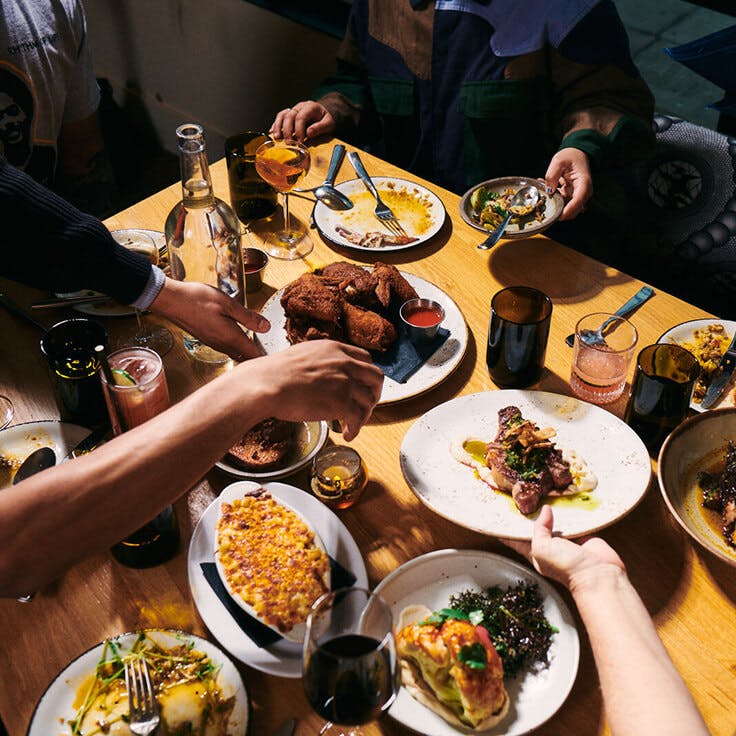 Alta Adams - Los Angeles, CA - several plated dishes serverd family-style with multiple people passing dishes