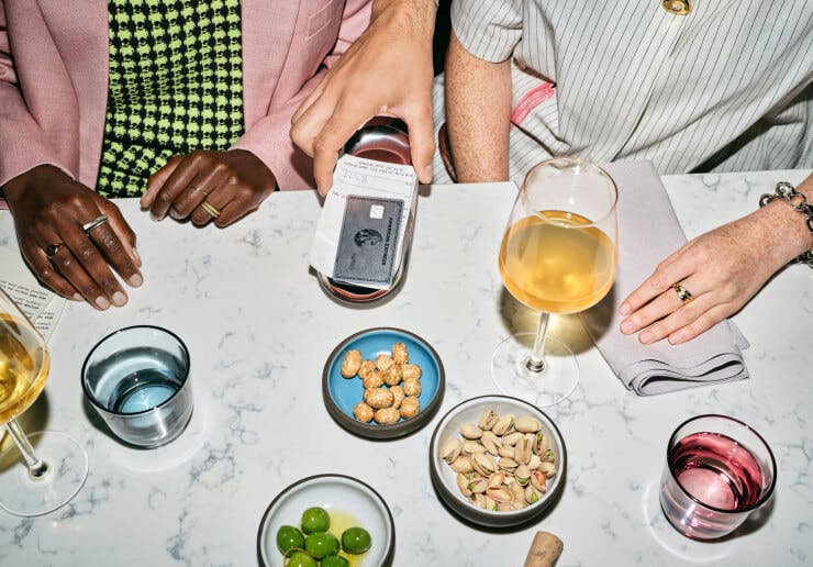 American Express card on a restaurant table next to a colorful plateware and glassware