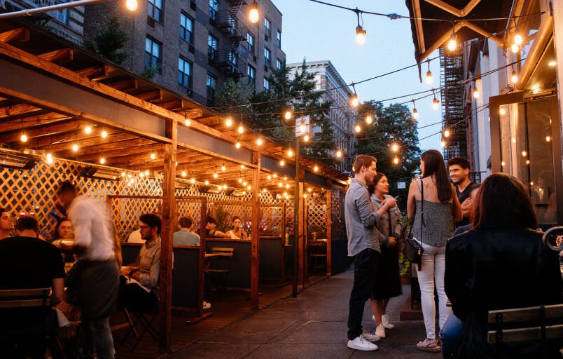L'Artusi - restaurant patio at twilight with glowing lights and people dining al fresco
