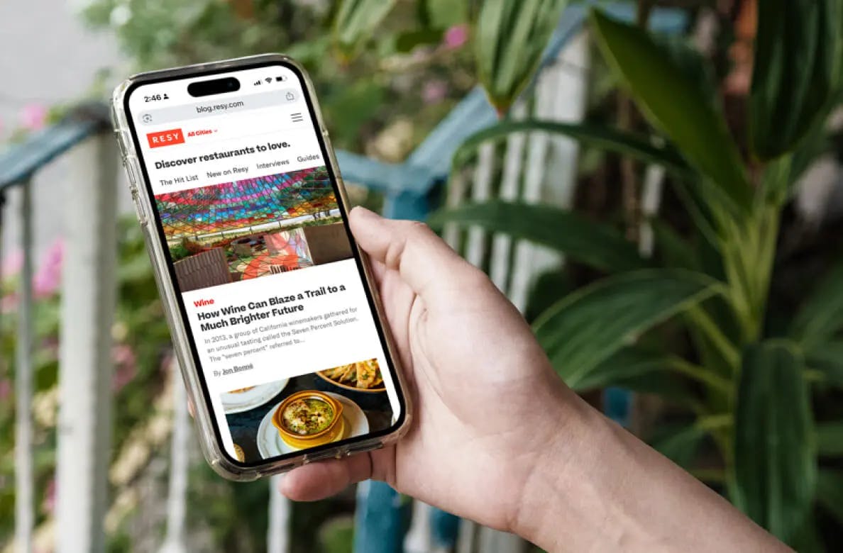 Person holding mobile device searching for restaurants with on Resy's mobile site
