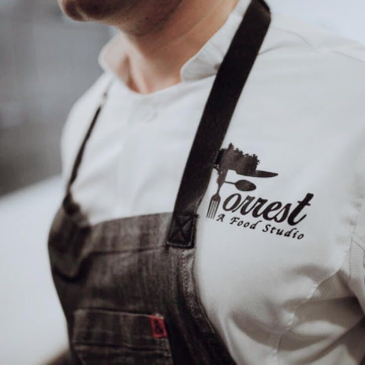 Closeup of chef from Forrest, A Food Studio with logo on shirt