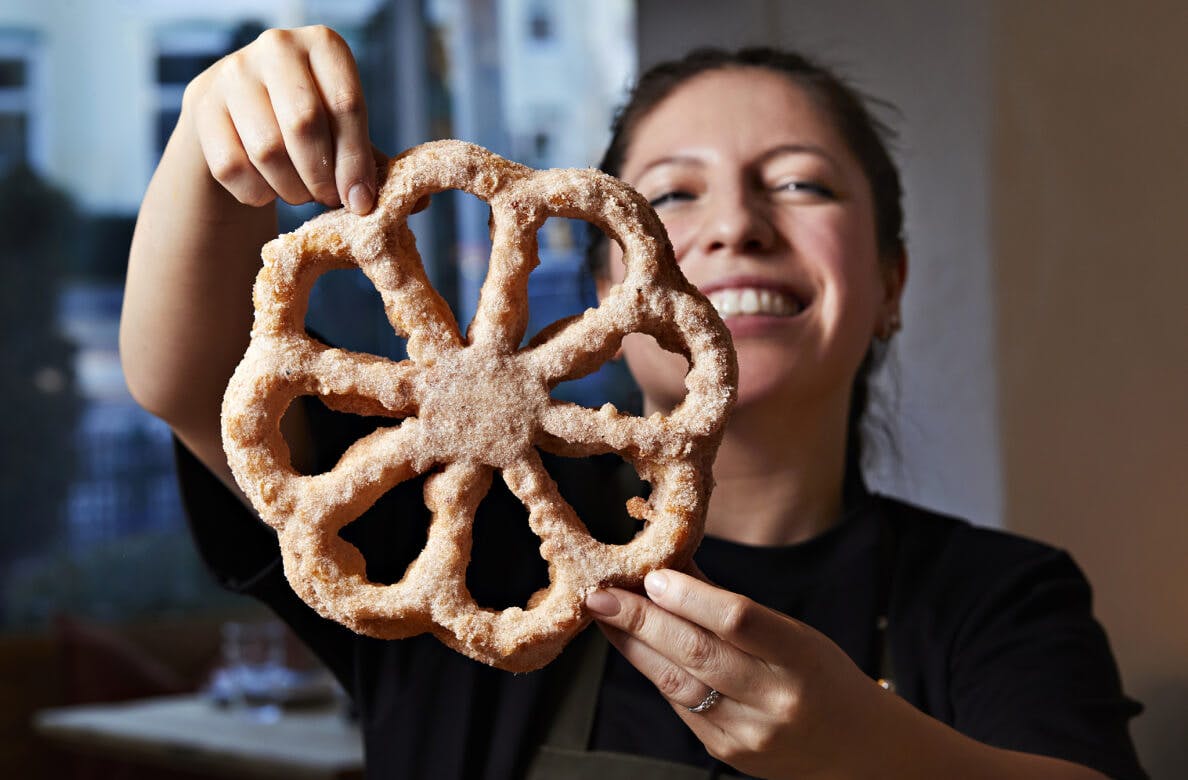 Patisserie chef displaying a large pastry in the shape of an outline of a flower