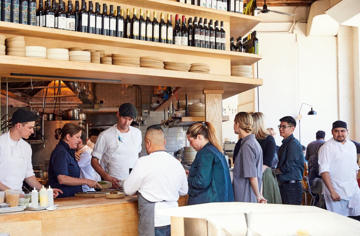 Diners and servers gathered around a wine bar built of okay with high ceilings